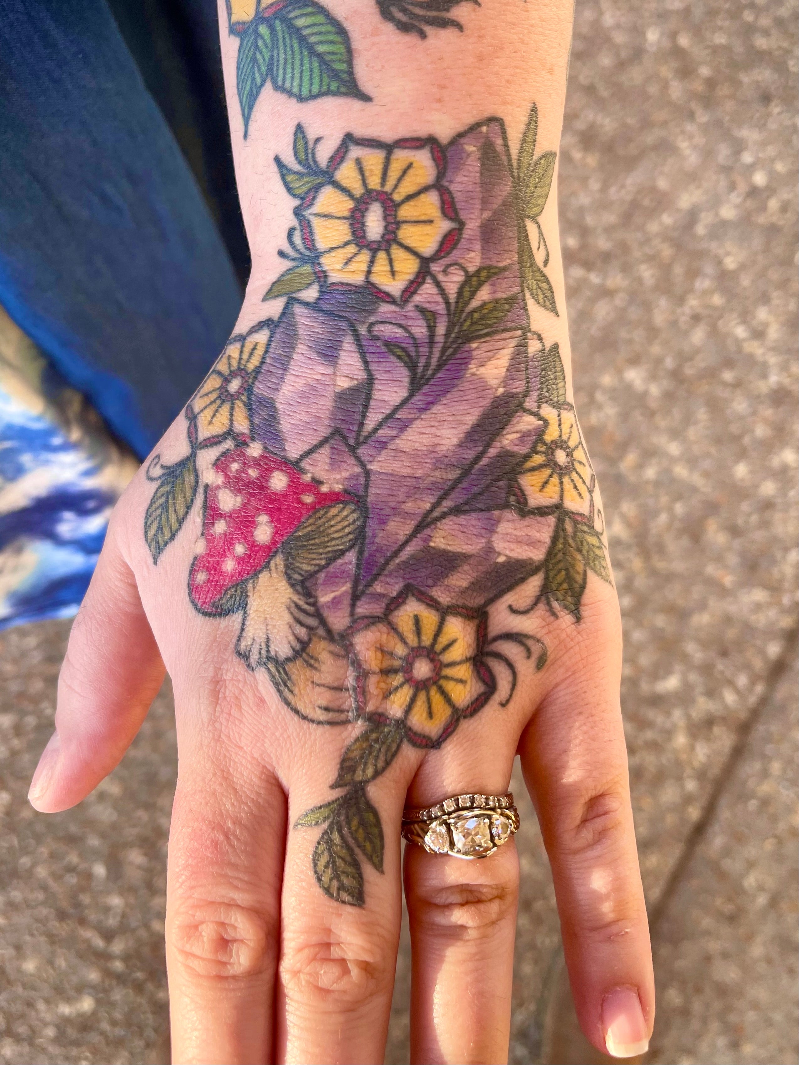 Hand Tattoo of an Amethyst Crystal with Amanita muscaria and yellow flowers by Shannon Byrd of Fayetteville, AR