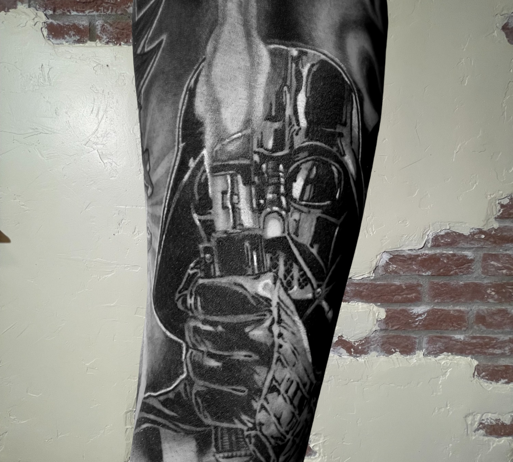 A black and white tattoo portrait of Darth Vader with his lightsaber by Shannon Byrd of Northwest Arkansas