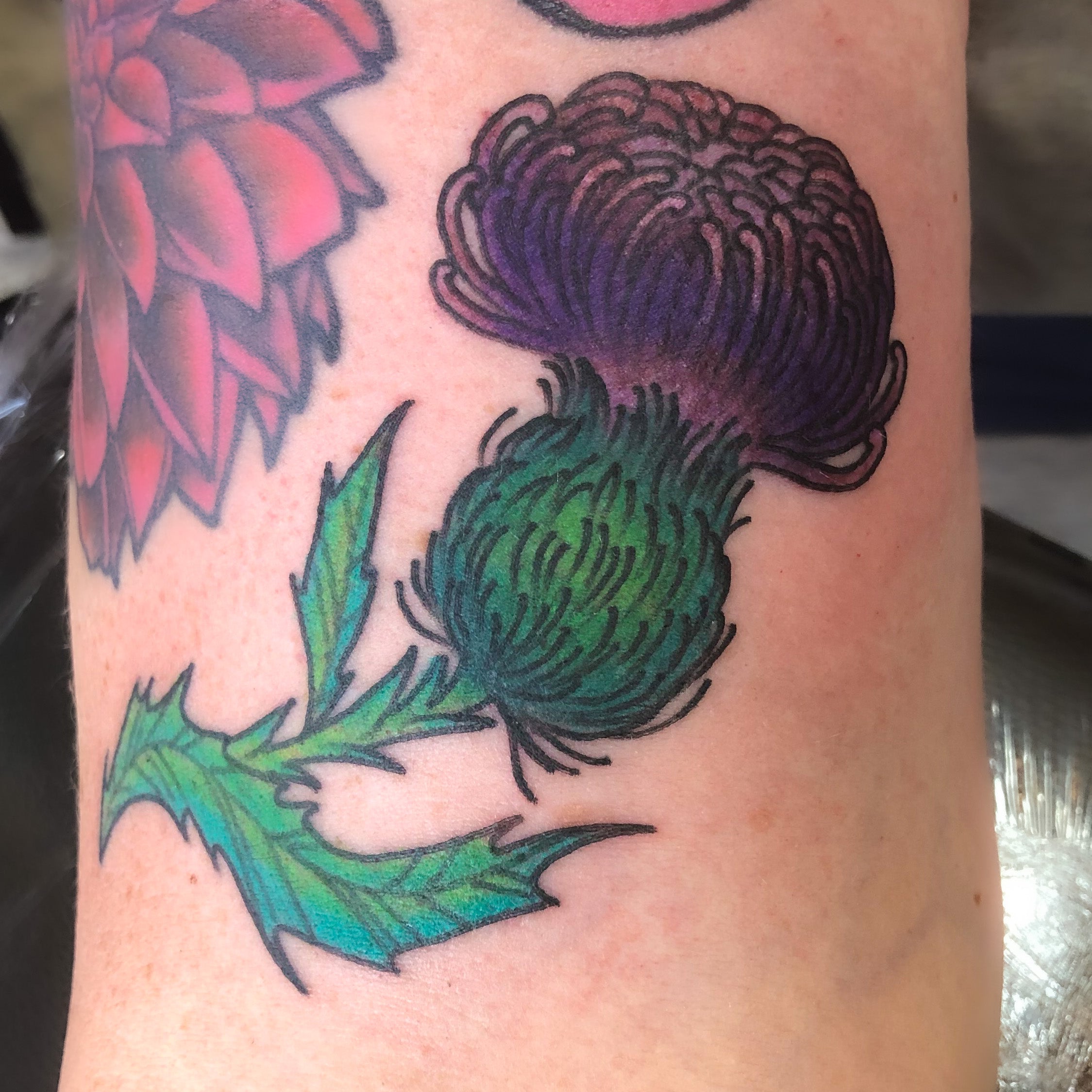 A tattoo of a purple thistle flower by Shannon Byrd of Fayetteville, AR